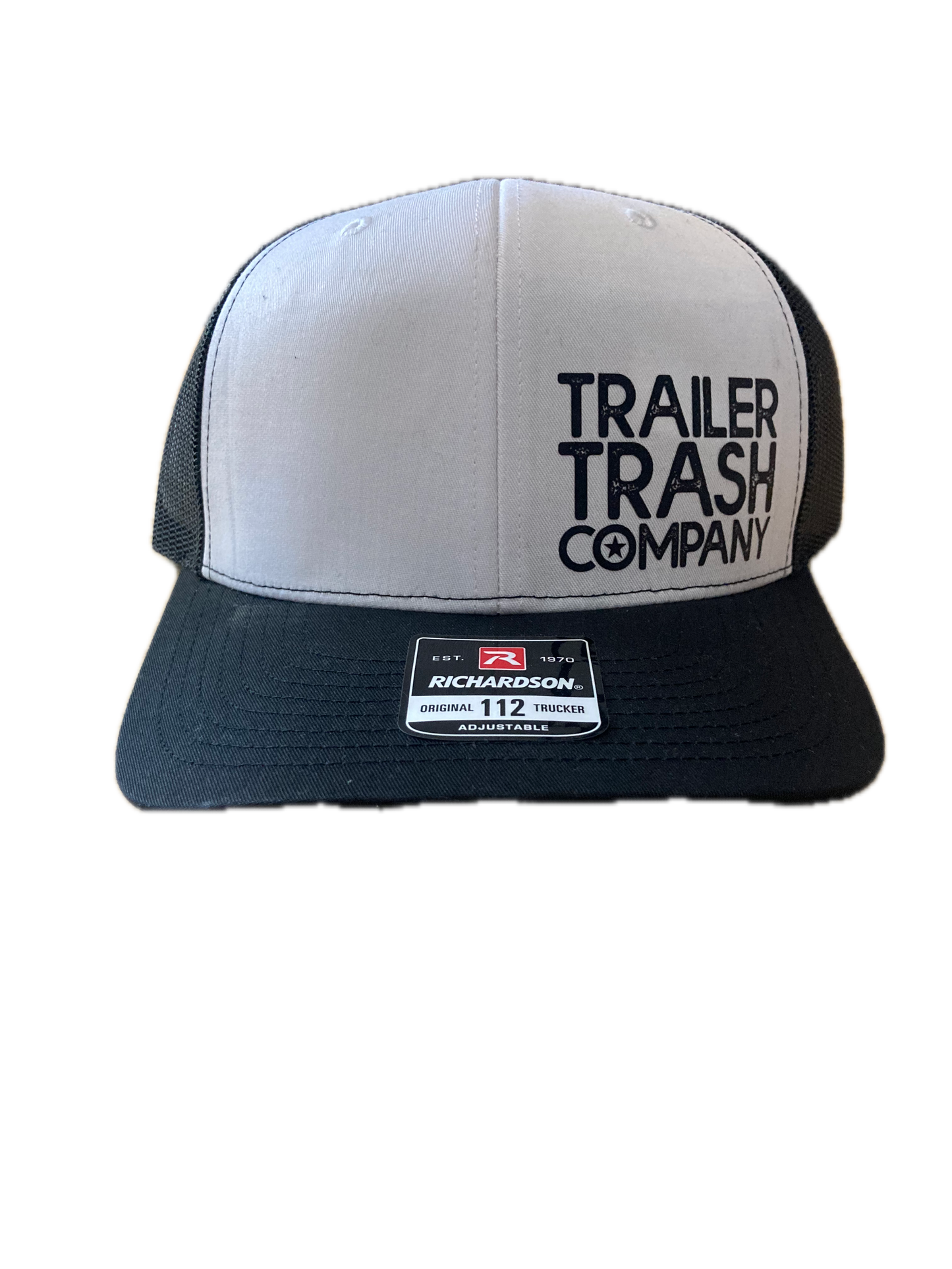 A black and white trucker hat with 'TRAILER TRASH COMPANY' printed on the front panel and a visible 'Moto 112' sticker on the side, shown against a plain white background.
